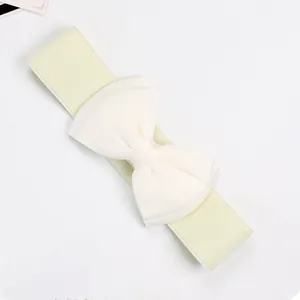 Macro detail of cream elastic waist belt featuring a large soft chiffon bow decoration