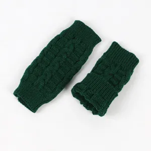 Detail showing the thick cable knit texture of dark green fingerless gloves.