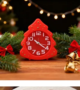 Close-up of a red Christmas tree shaped alarm clock surrounded by festive bells and pine branches