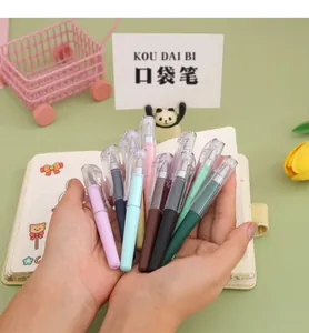 Hand holding multiple colorful mini gel pens against a pastel green stationery background.