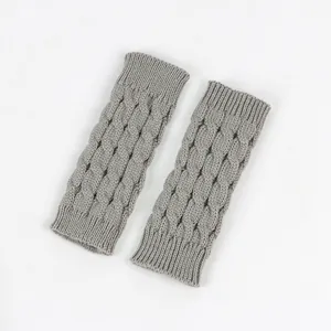 Close-up of grey cable-knit fingerless gloves showing detailed acrylic yarn texture
