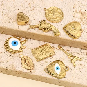 Détail de breloques en acier doré avec motifs œil et cœur pour la création de bijoux