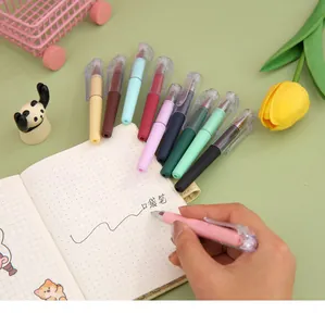 Detail shot of a hand writing with a pink mini portable gel pen in a dotted notebook