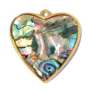 Primer plano macro de un colgante en forma de corazón de nácar de abulón con baño de oro