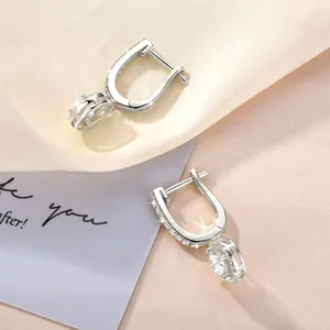 Detaillierte Makroansicht eleganter Silber-Moissanit-Ohrringe auf Seidenhintergrund.