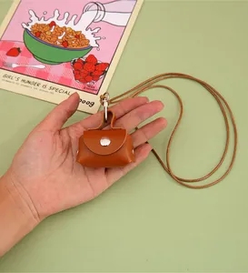 Close-up of a stylish mini tan PU leather pouch held in hand with a long neck lanyard