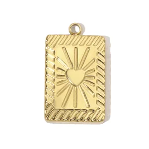 Vue détaillée d'un pendentif rectangulaire doré orné d'un motif cœur et de rayons de soleil.