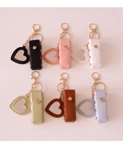 Detail view of six colorful leather lipstick holder keychains with heart mirrors on white.