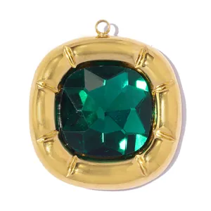 Close-up of a gold-toned square pendant featuring a faceted green gemstone centerpiece