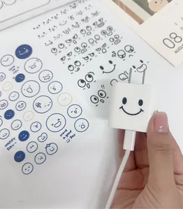 Close-up of cute cartoon smiley face stickers on a white charger adapter detail
