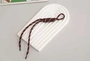 Close-up detail of a brown minimalist nylon phone lanyard with white contrast stitching