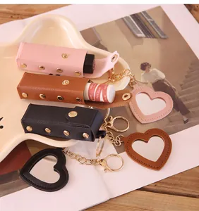 Macro detail of portable leather heart lipstick cases with built-in mirrors and gold keychains