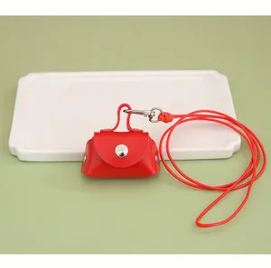 Detailed view of a mini red PU leather coin purse with red lanyard on a white tray