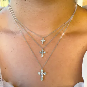 Close-up of three layered cross necklaces with sparkling moissanite stones on a model
