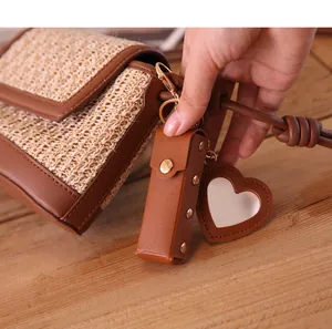 Detailed macro view of brown leather lipstick holder with heart mirror charm on bag