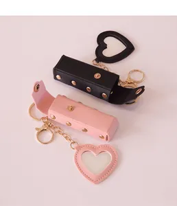 Close-up of portable leather lipstick cases with heart-shaped mirrors in pink and black