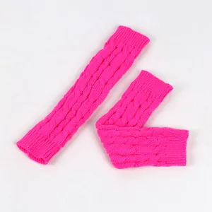 Dettaglio di manicotti lavorati a maglia rosa neon con una trama a treccia spessa