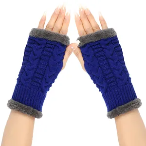 Detail of blue cable-knit fingerless gloves with grey faux-fur trim on white background