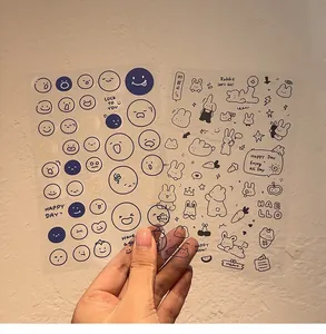Close-up view of transparent PVC cartoon emoji and rabbit stickers for DIY journal decoration.