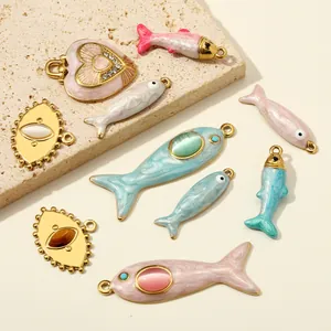 Dettaglio macro di ciondoli smaltati a forma di pesce e cuore con pietre