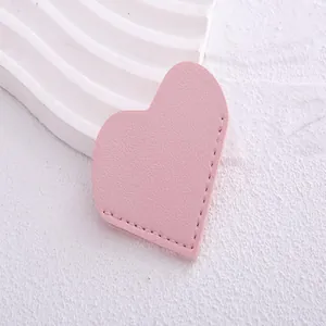 Close-up view of a pink heart-shaped leather corner bookmark with stitched edges