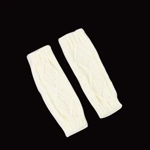 Détail de chauffe-bras en maille torsadée blanche avec motif losange sur fond noir