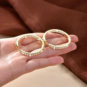 Detailansicht luxuriöser 14k vergoldeter Kristall-Creolen in der Handfläche gehalten