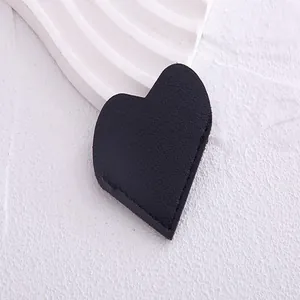 Macro view of a black heart-shaped PU leather corner bookmark on white texture