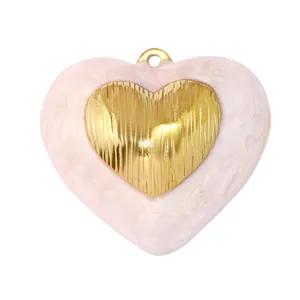 Macro detail of French vintage heart-shaped pendant in pink resin and gold metal.