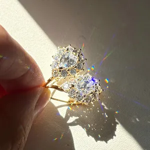 Vista macro de pendientes de botón de halo de moissanita en forma de pera con fuego de arco iris