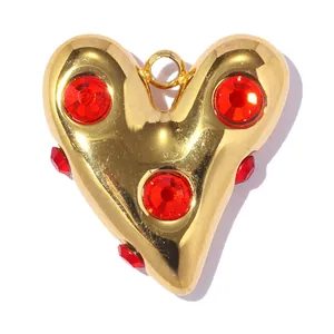 Gros plan d'un pendentif en acier doré en forme de cœur avec des strass rouges