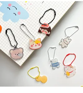 Set kawaii acryl sleutelhangers met gekleurde kogelkettinkjes op een ruitjesnotitieboek