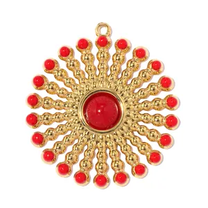 Detailed view of a gold-plated sunburst pendant with red beads and central cabochon