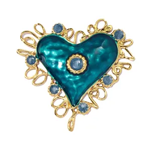 Detailed view of a vintage teal enamel heart pendant with gold-tone filigree and blue stones.