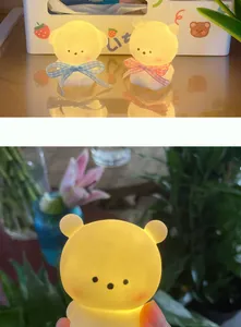 Warm glowing bear night light detail with checkered bow decoration and soft ambient light