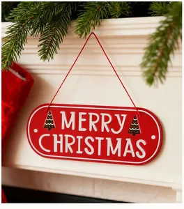 Red metal Merry Christmas hanging sign on a white mantel with festive pine branches