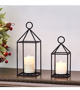 Detailed macro view of two black geometric metal candle lanterns on a dark wooden surface