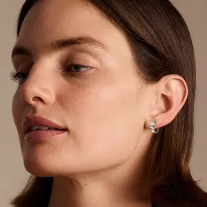 Close-up view of a model wearing sparkling three-stone moissanite hoop earrings