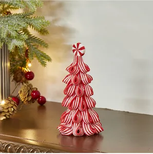 Primo piano di un albero di Natale in argilla a strisce bianche e rosse su un caminetto.