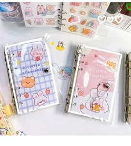 Nahaufnahme eines süßen Cartoon-Ringbuch-Sets mit transparenter PVC-Hülle und Anhängern