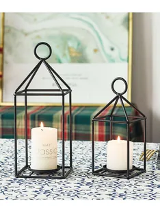 Minimalist black metal candle lanterns on a patterned tablecloth with warm lighting