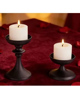 Macro view of black vintage iron candle holders with lit white candles on red velvet
