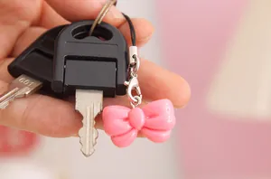 Close-up of a cute pink resin bow charm attached to a key ring and mobile phone strap