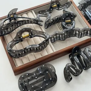 Assorted dark grey translucent hair claws with white polka dot patterns on display