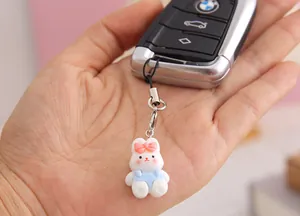 Close-up of a cute white resin rabbit charm with a pink bow hanging from a car key holder