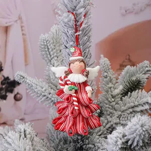 Angelo di Natale in pasta polimerica a forma di albero appeso a un ramo di pino innevato