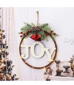 Detail view of a festive Christmas door wreath with JOY letters, pine needles, and LED lights.