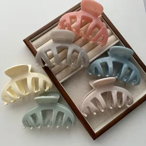 Elegant multi-colored acrylic pumpkin hair claw clips set in a wooden display tray