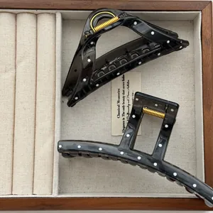 Close-up of black translucent polka dot hair claw clips in a wooden jewelry box