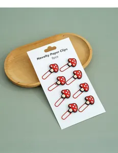 Detail of 8-piece novelty mushroom-shaped red cartoon metal paper clips on white card.